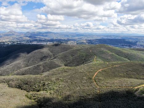 Aerial view of Black Mountain in Carmel Valley, San Diego, California, USA. Green dry mountain during sunny cloudy day with hiking trails, perfect for sport activity an leisure time..