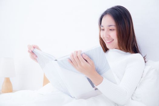 Asian woman reading a book and smiling in bedroom. lifestyle concept.