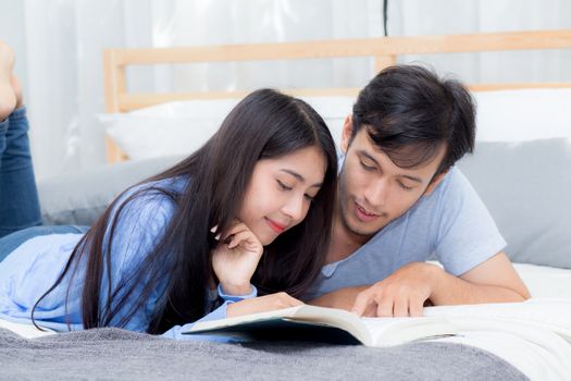 Couple reading a book together in bedroom on the morning with happiness.