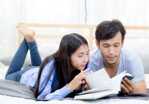 Couple reading a book together in bedroom on the morning with happiness.