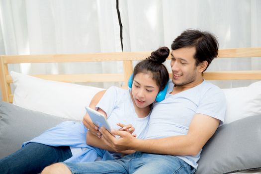 Beautiful asian young couple listening to music with tablet on bed, Love, dating,Young couple in sitting together in bed using a Tablet.