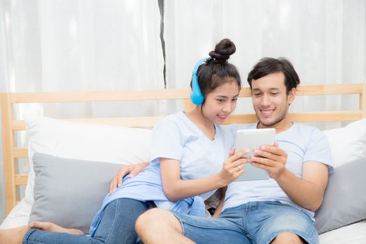 Beautiful asian young couple listening to music with tablet on bed, Love, dating,Young couple in sitting together in bed using a Tablet.