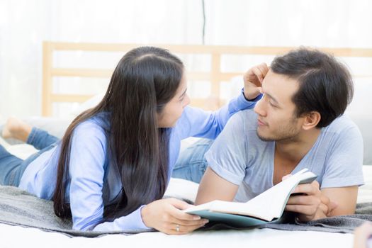 Couple reading a book together in bedroom on the morning with happiness.