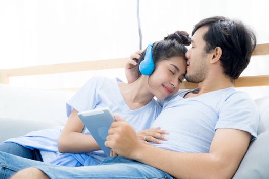 Beautiful asian young couple listening to music with tablet on bed, Love, dating,Young couple in sitting together in bed using a Tablet.