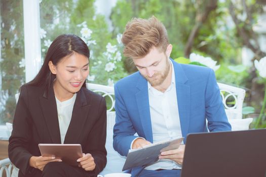 technology and office concept - two business man and woman with laptop - tablet pc computer and clipboard document having discussion in office.