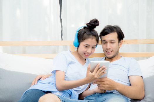 Beautiful asian young couple listening to music with tablet on bed, Love, dating,Young couple in sitting together in bed using a Tablet.