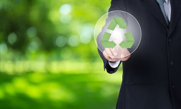 business man finger pointing at paper green recycle symbol with nature background, environment concept.