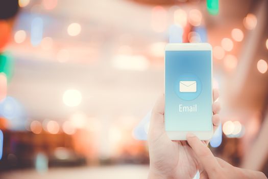 Hand holding man check and sending message with email in a phone on bokeh background, communication concept.