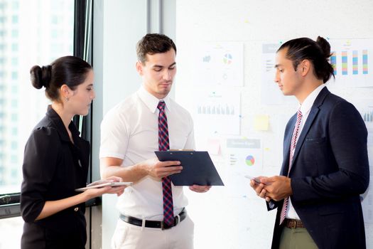 young businessman holding clipboard with present profit and secretary while giving presentation in office and talking business people other, teamwork concept.