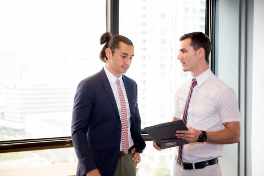 American young businessman two people holding clipboard and discussing work in the meeting room, business concept.