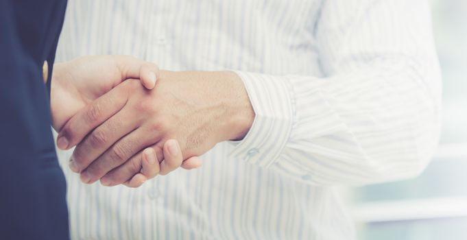 Handshake of businessman and businesswoman after successful business meeting with text partnership.