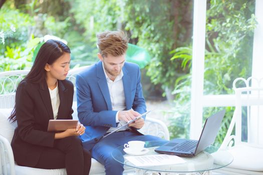 technology and office concept - two business man and woman with laptop - tablet pc computer and clipboard document having discussion in office.