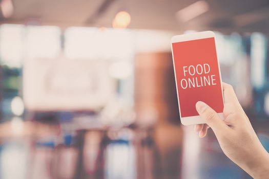 Hand holding phone with food order online with blur of restaurant background, order food online business concept.