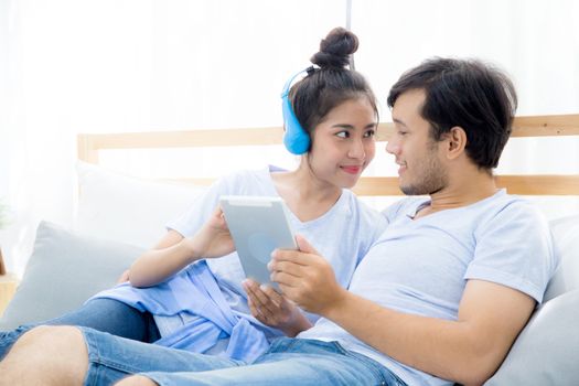 Beautiful asian young couple listening to music with tablet on bed, Love, dating,Young couple in sitting together in bed using a Tablet.