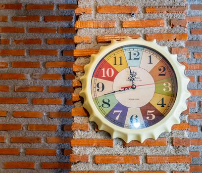 Stylish analog clock hanging on brick wall. Space for text