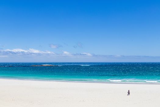 Camps Bay Beach in Cape Town, South Africa. Walking tourists on white sand.