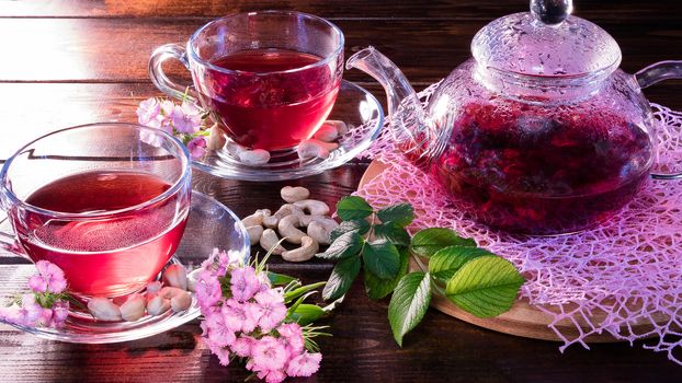 Green tea leaves or leaves of medicinal herbs lie on the table with a teapot and mugs of red tea, cashew nuts and clove flowers. Tea parties, tea traditions and ceremonies. Zen traditions of the East