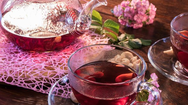 Tea parties, tea traditions and ceremonies. Zen traditions of the East.Green tea leaves or leaves of medicinal herbs lie on the table with a teapot and mugs of red tea, cashew nuts and clove flowers