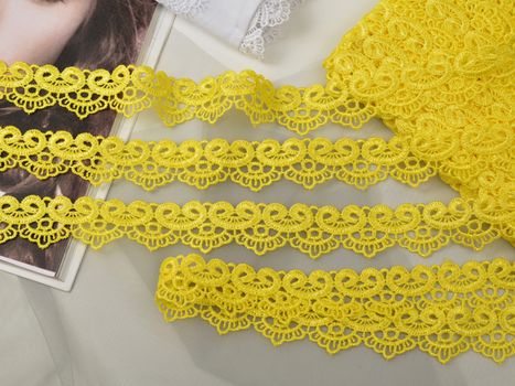 Tapes of yellow gentle guipure, beauty lace fabric. Elastic material. Using for Atelier and needlework store. Space for text. repeating pattern and interweaving threads. texture for websites