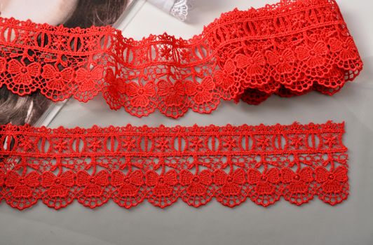 Tapes of red gentle guipure, beauty lace fabric. Elastic material. Using for Atelier and needlework store. Space for text. repeating pattern and interweaving threads. texture for websites