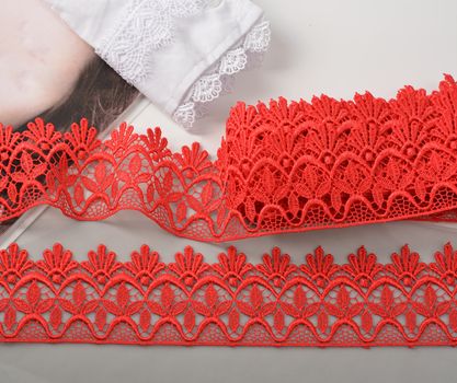 Tapes of red gentle guipure, beauty lace fabric. Elastic material. Using for Atelier and needlework store. Space for text. repeating pattern and interweaving threads. texture for websites