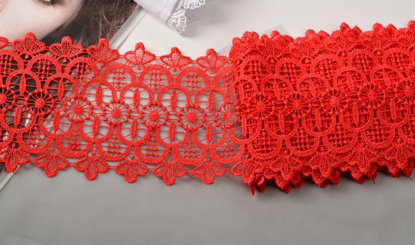 Tapes of red gentle guipure, beauty lace fabric. Elastic material. Using for Atelier and needlework store. Space for text. repeating pattern and interweaving threads. texture for websites