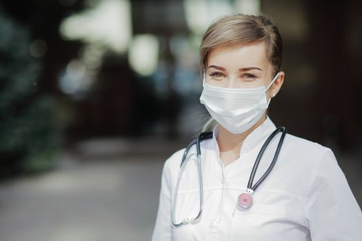 Confident female doctor or nurse wearing a face protective mask. Safety measures against the coronavirus. Prevention Covid-19 healthcare concept. Stethoscope over the neck. Woman, girl.