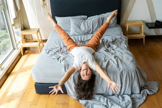 Beautiful young brunette girl fooling around on the bed. View from above. Good mood.