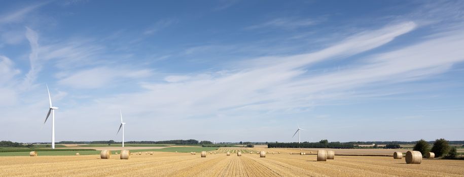 fields and wind turbines in french part nord pas de calais under blue sky in summer