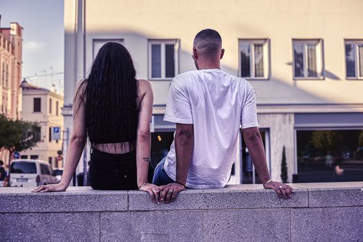 Young Love Couple sitting on a low wall in the city