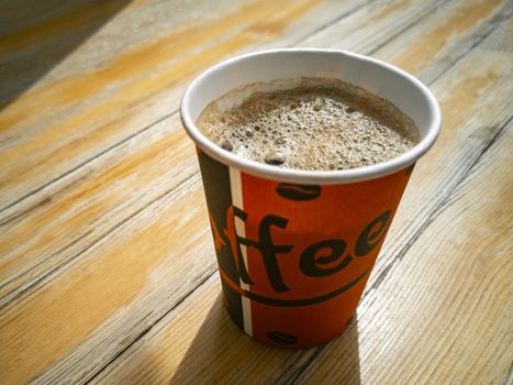 Red paper cup with coffee to go on wooden ground. Leherheide, Bremerhaven.