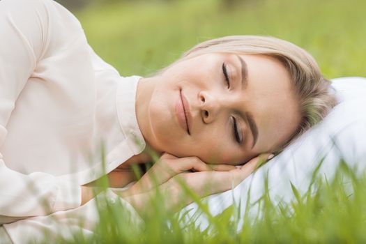 Young woman sleeping on soft pillow in fresh spring grass