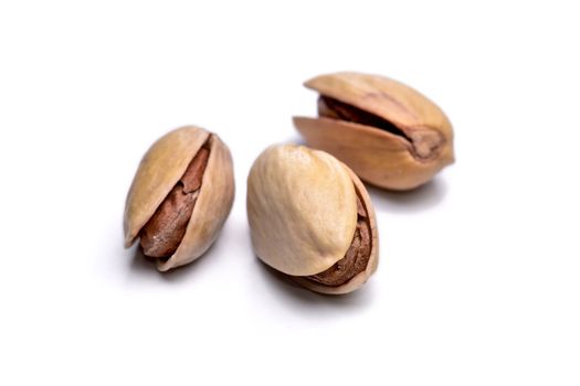 Three roasted pistachio nuts (Pistacia vera) isolated on white