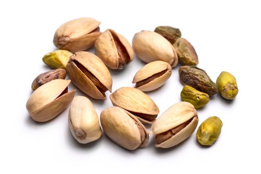 Pile of roasted pistachio nuts (Pistacia vera) isolated on white