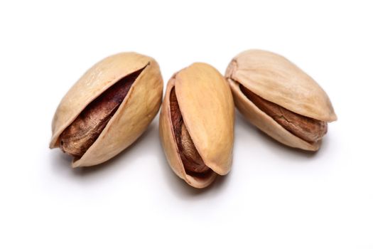 Three roasted pistachio nuts (Pistacia vera) isolated on white