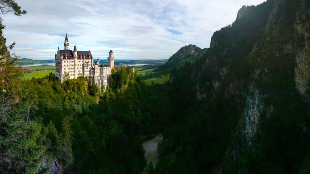 Neuschwanstein Castle in Schwangau, Germany with dark forest and rocks in foreground