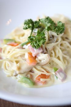 Spaghetti with mushroom and ham white sauce on wood background