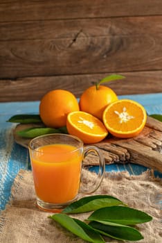 Fresh orange and a glass of orange juice on a wooden table background.
