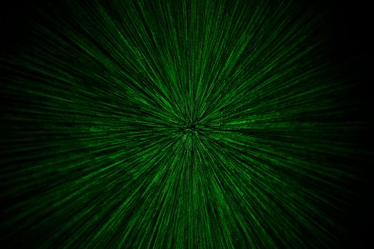 natural lens zoom explosion radial blurred green particles on black background with selective focus.