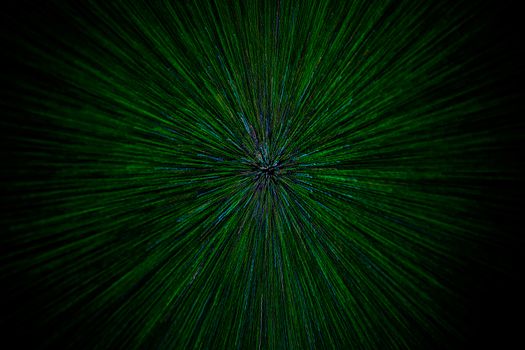 natural lens zoom explosion radial blurred green particles on black background with selective focus.