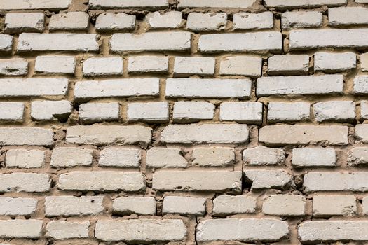 Deep cracked white silicate brick wall closeup texture and background. Horizontal shot.