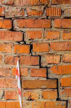 Deep cracked orange brick wall closeup texture and background. Vertical shot.