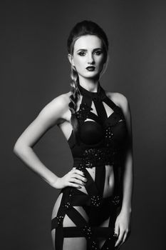 white girl modell on a dark background in a dress made of cut stripes of black fabric