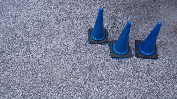 Blue color plastic material traffic cones and old grey color textured cement road floor in Osaka Japan.