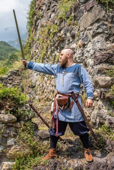 Medieval warrior brandishes his sword raising it to the sky, Viking in traditional clothes