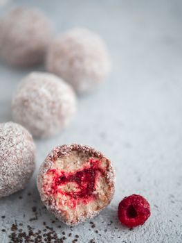 Raw vegan lamington bliss balls with raspberries chia jam on gray background. No baked healthy vegan sweet dessert idea and recipe. Copy space for text.