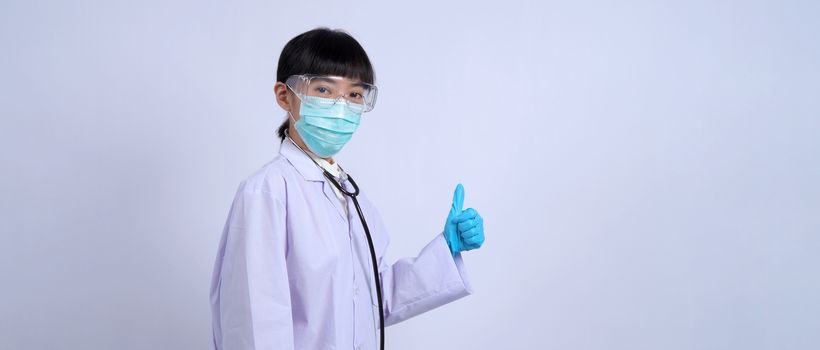 Asian woman doctor pointing finger out to copy space beside her and she wearing white color suit and medical mask and blue rubber gloves to prevent virus pandemic and stethoscope on neck.