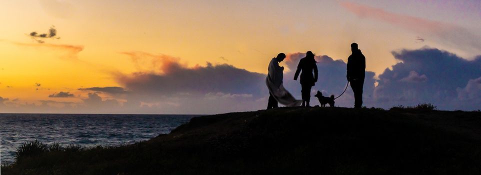 Romantic sunset of friends with dog on sea beach