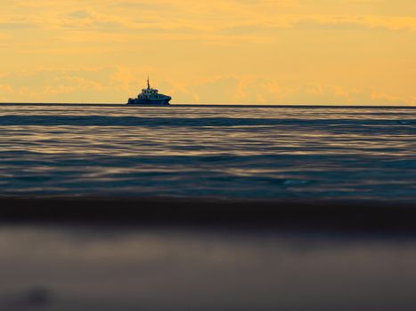 One small fishing boat heading out on the foggy ocean at dawn. Boat on the background of sunset. The Baltic Sea close up, stormy dramatic dark clouds. The Vacation, summer concept