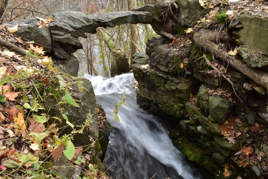 A Long Exposure of Fast Moving Water Flowing Under a Natural Stone Arch Over a Cliff